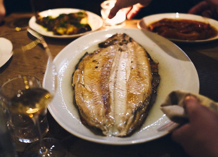 Roasted fish on a plate at a restaurant table.