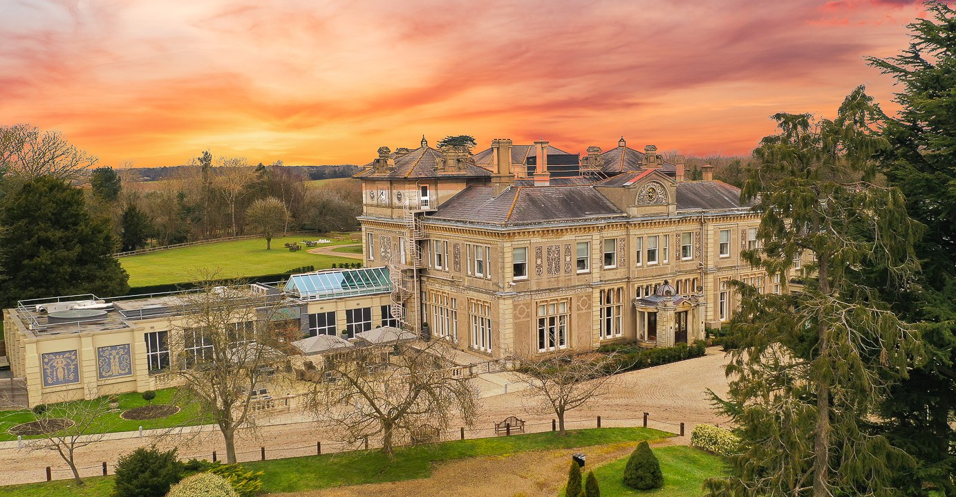 Aerial view of Down Hall Hotel at sunset.