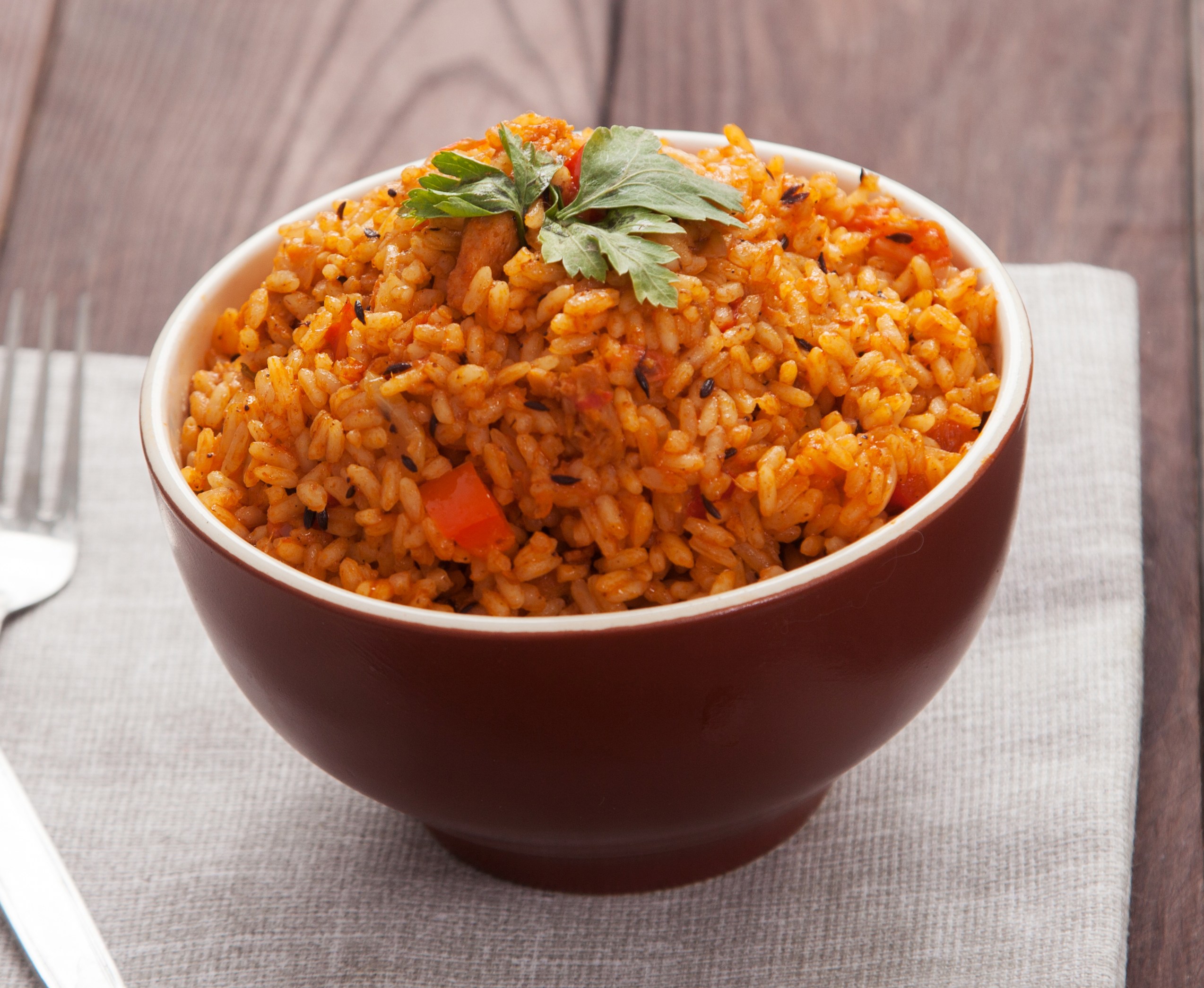 Bowl of jollof rice with tomatoes and peppers.