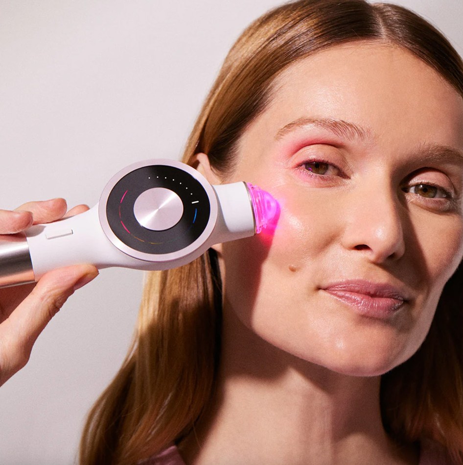 Woman using a light therapy device on her face.