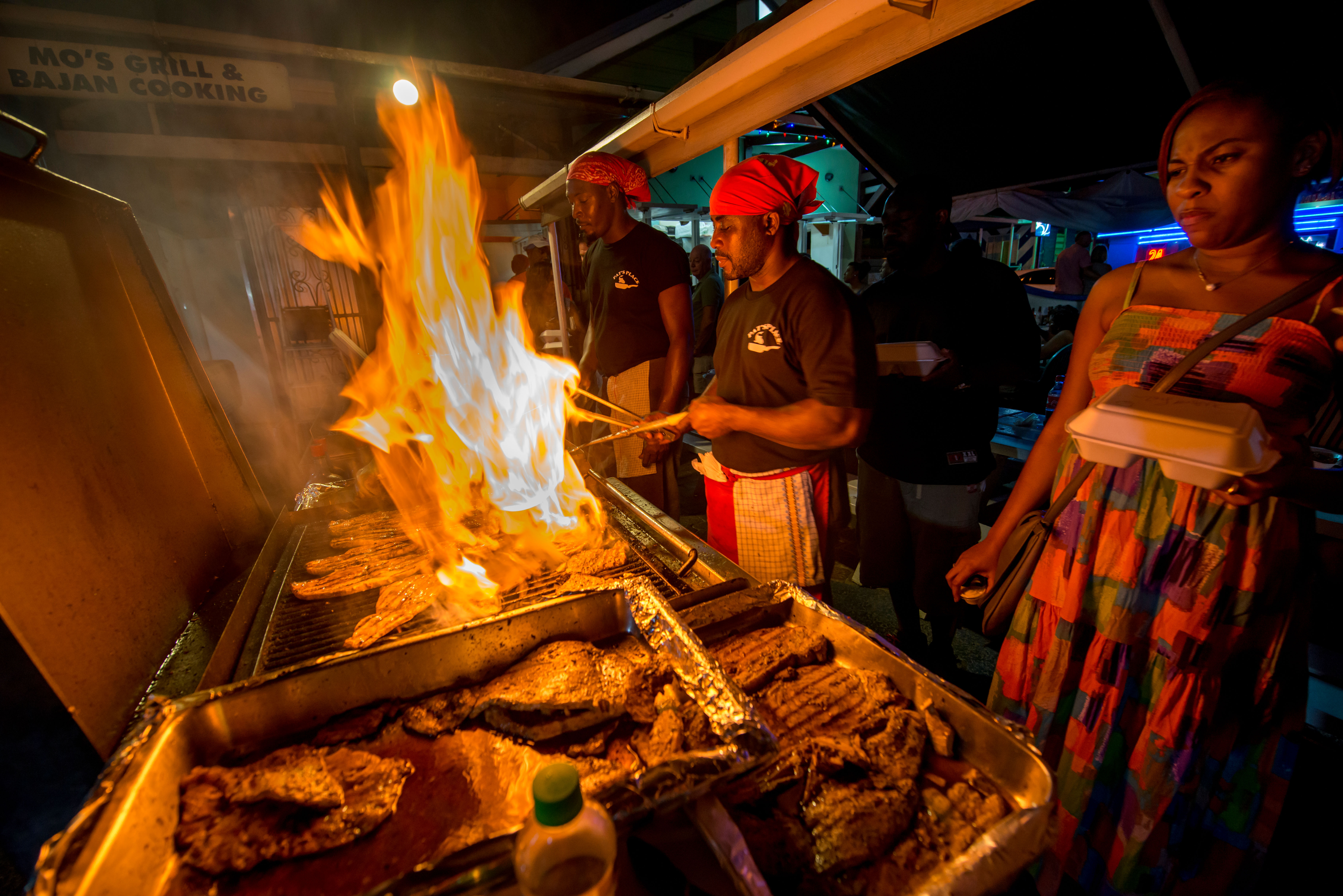 Cooks grilling fish at a nighttime barbeque.